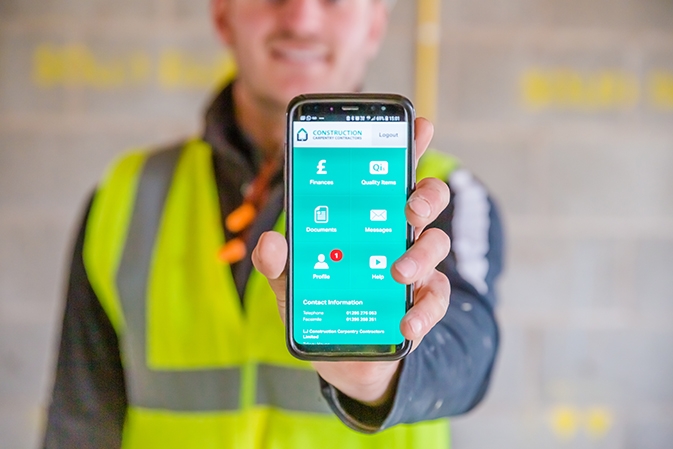 LJ Construction worker holding their smartphone displaying their site management software